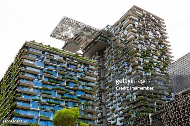 low angle view of apartment buildings swith vertical gardens and heliostat, sky background with copy space - environmental conservation office stock pictures, royalty-free photos & images