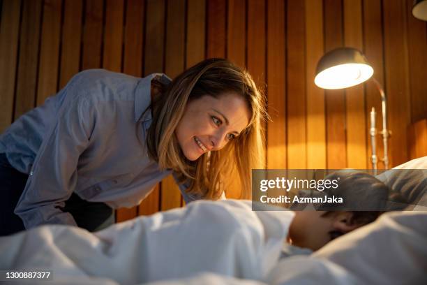 mère tucking son fils au bâti - heure du coucher photos et images de collection