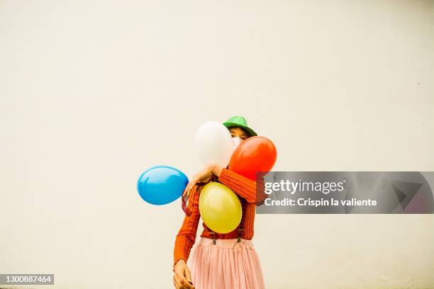 woman with colorful balloons and protective mask at carnival - funny surgical masks stock-fotos und bilder