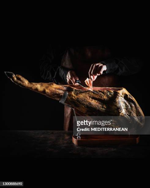 iberian ham serrano ham cutting slice male hands and knife on dark moody - iberian pig stock pictures, royalty-free photos & images