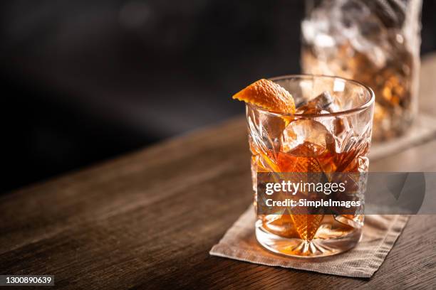 old fashioned whiskey drink on ice with orange zest garnish. - old fashioned cocktail stock pictures, royalty-free photos & images