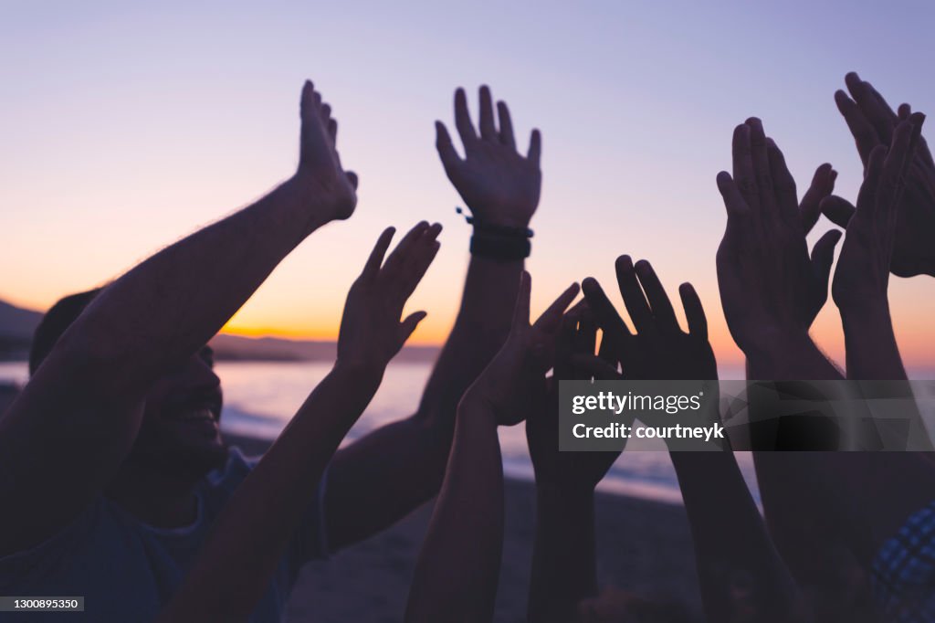 Silhouet van een Groep mensen met hun opgeheven handen bij zonsondergang of zonsopgang.