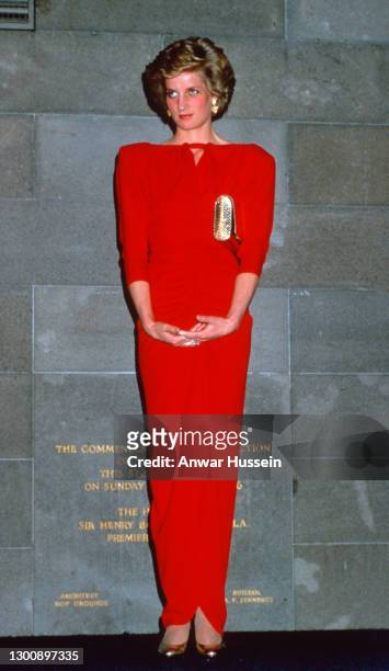 Diana, Princess of Wales, wearing a red dress with shoulder pads designed by Bruce Oldfield and a gold clutch bag, attends a state reception at the...