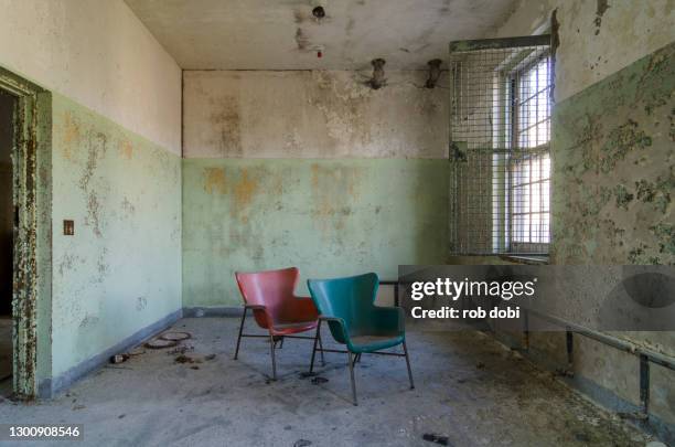 two colored chairs inside a decaying abandoned asylum - psychiatric hospital stock pictures, royalty-free photos & images