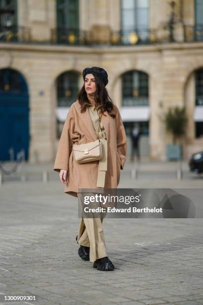 Sara Carnicella wears a blue checked wool beret hat from Anthony Peto, a brown turtleneck wool pullover, a pale brown wool long oversized coat from...