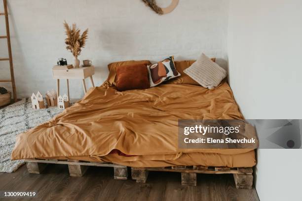 bed in the bedroom. blanket on a brown bed in a natural bedroom area with dried flowers and a wooden bedside table. - beige bedroom stock pictures, royalty-free photos & images