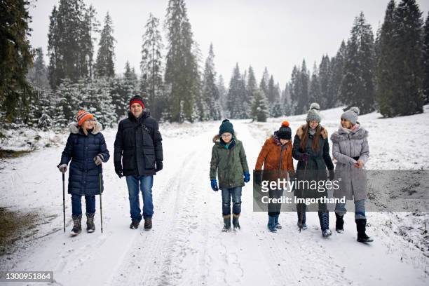 multi generation family enjoying hiking in winter forest. - multi generation family winter stock pictures, royalty-free photos & images