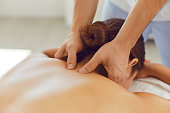 Young woman enjoying relaxing remedial body massage done by professional masseur