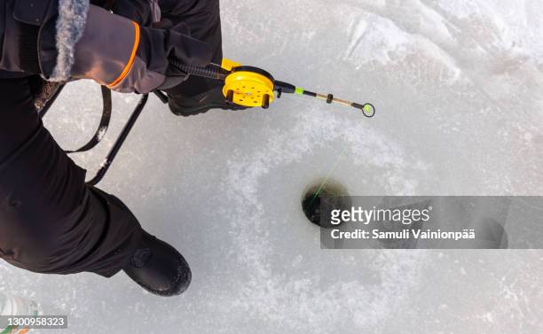high angle view of fishing rod over hole in frozen lake - ice fishing stock pictures, royalty-free photos & images