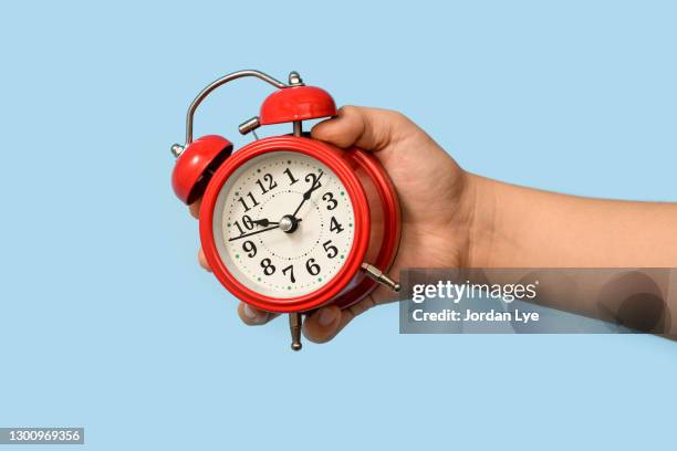 cropped hand of boy holding alarm clock - tijdmeter stockfoto's en -beelden