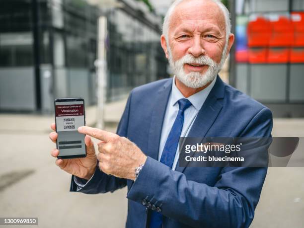 businessman holding certificate of covid-19 vaccination - border crossing point stock pictures, royalty-free photos & images