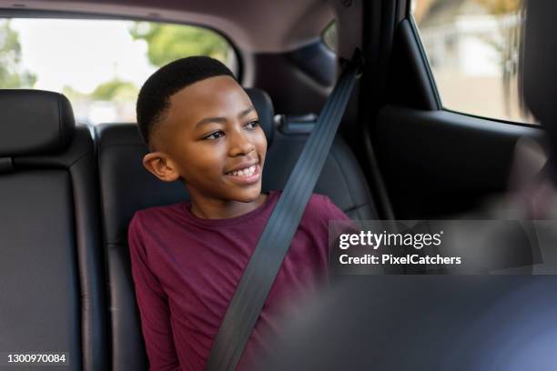 jovencito con cinturón de seguridad mirando por la ventana del coche - cinturón de seguridad fotografías e imágenes de stock