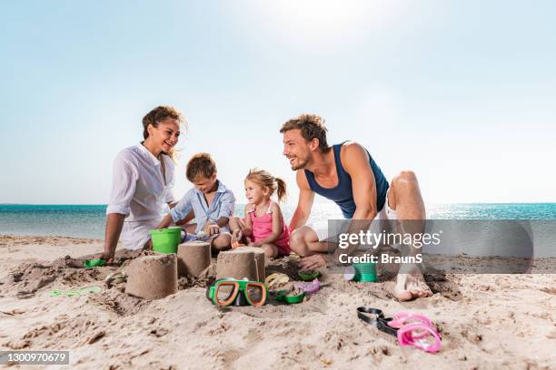 glückliche eltern und ihre kleinen kinder spielen im sand am strand. - sandburg stock-fotos und bilder