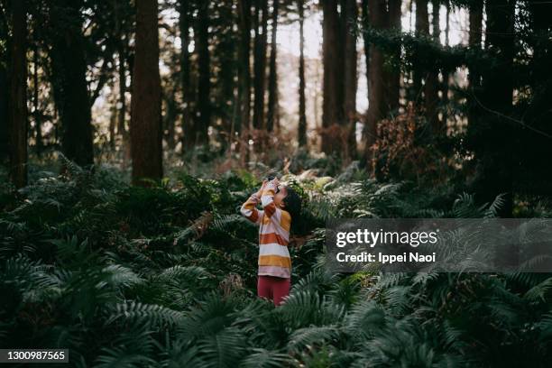 young girl looking through binoculars in forest in winter - children nature photos et images de collection