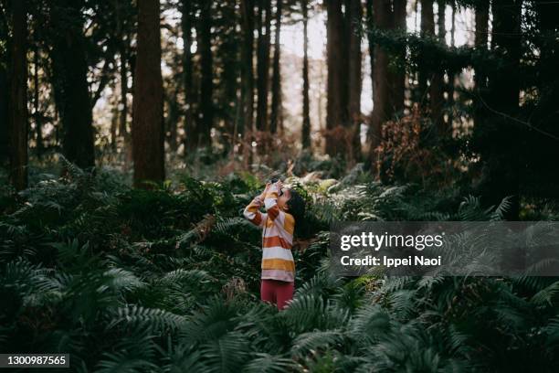 young girl looking through binoculars in forest in winter - child looking up stock pictures, royalty-free photos & images