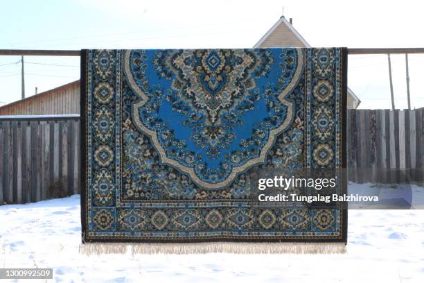 Dusty Carpet Cleaning Outdoor on Back Yard in Winter with Oriental Pattern Texture
