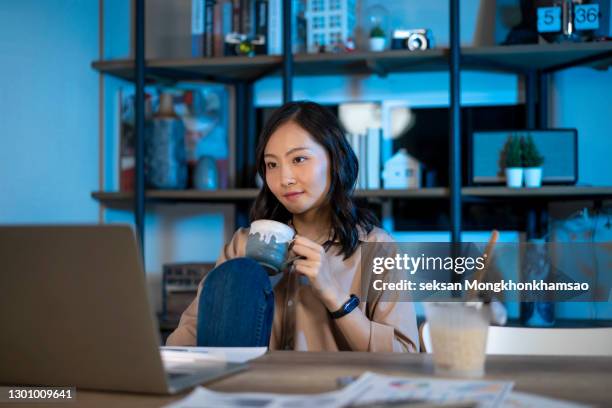 happy woman with headphones surfing the net on desktop pc at night - leisure work coffee happy stockfoto's en -beelden