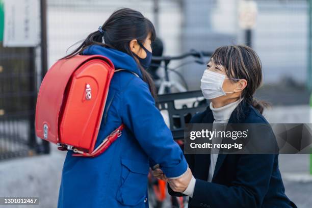 mother and daughter separating in front of school building - covid commuter stock pictures, royalty-free photos & images