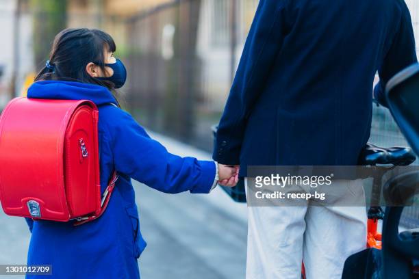 朝、通りを歩く母と小学生。学校に行く娘を働きに行く母親 - working mother ストックフォトと画像
