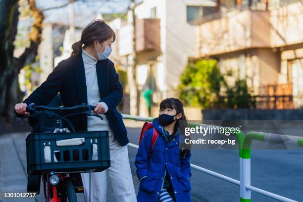 mother and elementary age child walking together in street in morning. mother going to work daughter going to school - businesswoman mask stock pictures, royalty-free photos & images