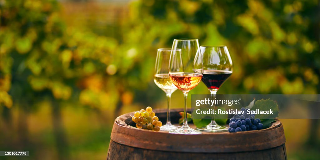 Three glasses of white, rose and red wine on a wooden barrel