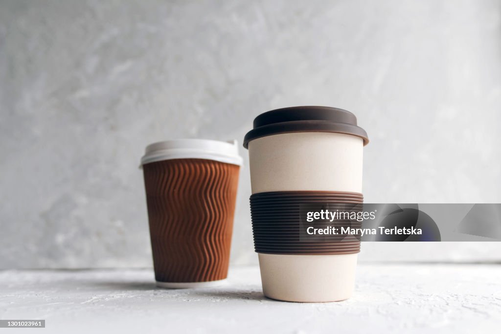 Reusable ecological cup with disposable paper cups in a modern composition.