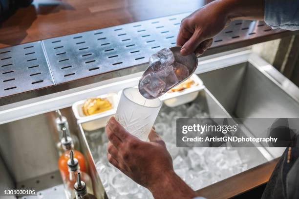 primo piano delle mani del barista che mettono il ghiaccio in un bicchiere. - portaghiaccio foto e immagini stock