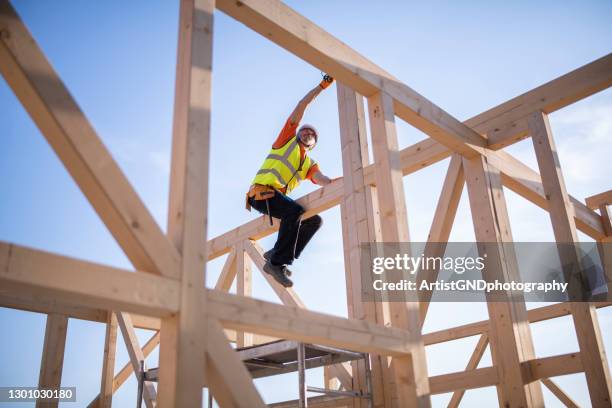 senior builder arbeitet auf dem dach eines holzhauses. - holzbalken stock-fotos und bilder