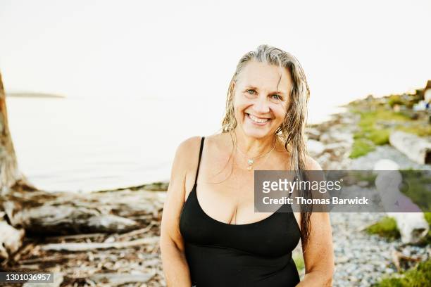 portrait of smiling senior woman standing on beach after swim on summer evening - decollete photos et images de collection