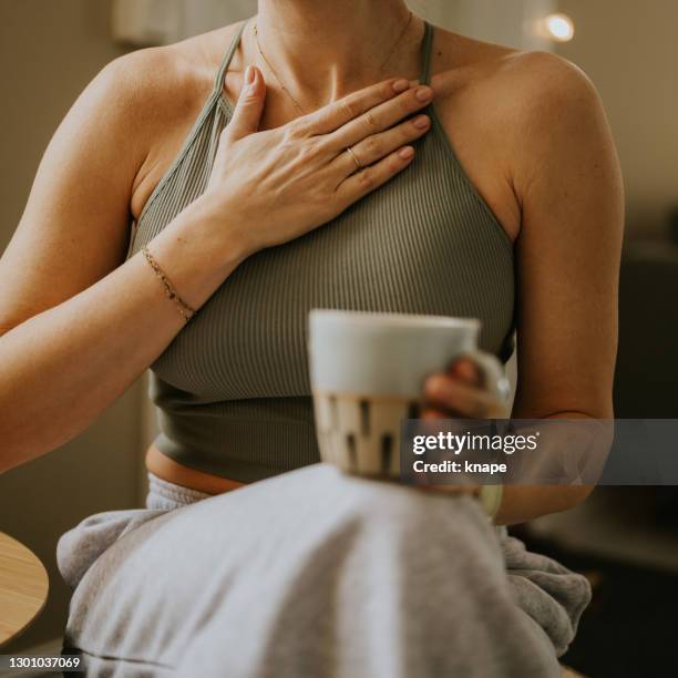 woman with hand on chest heart for breathing calming exercise feeling gratitute - hand on female chest stock pictures, royalty-free photos & images