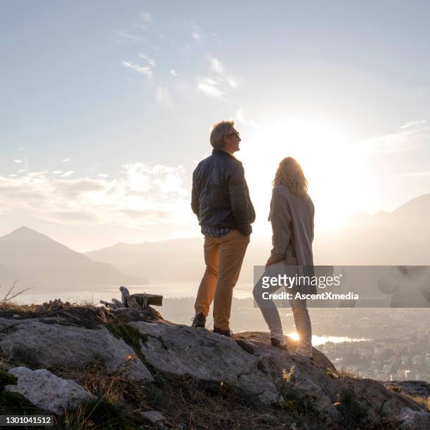 mature couple hike along sunny mountain ridge, sunset - lake sunset stock pictures, royalty-free photos & images