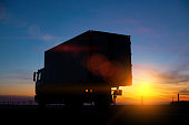 Truck driver transports cargo on a truck against the backdrop of sunset at night. The concept of compliance with the work and rest regime of drivers