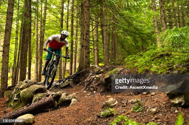 male mountain biker riding in a forest - mountain biker stock pictures, royalty-free photos & images