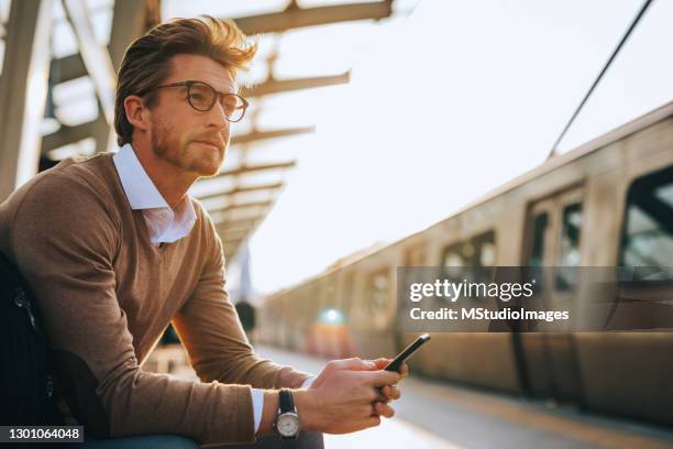 young man using mobile phone - plataforma de estação de metro imagens e fotografias de stock