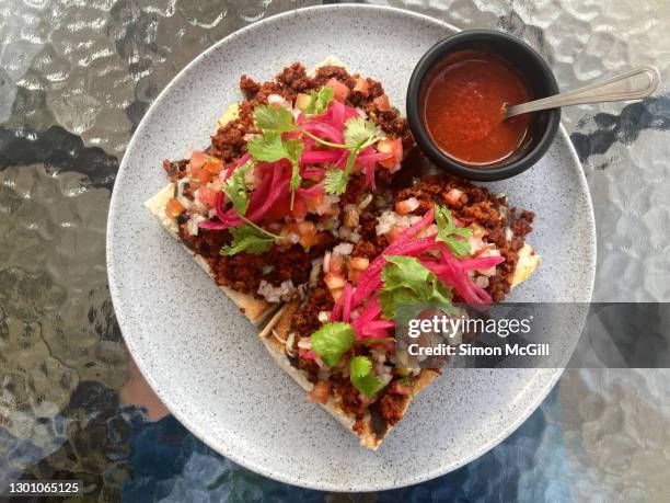 plate of molletes with longaniza sausage and serrano chili salsa sauce on a glass table top - ramequin photos et images de collection