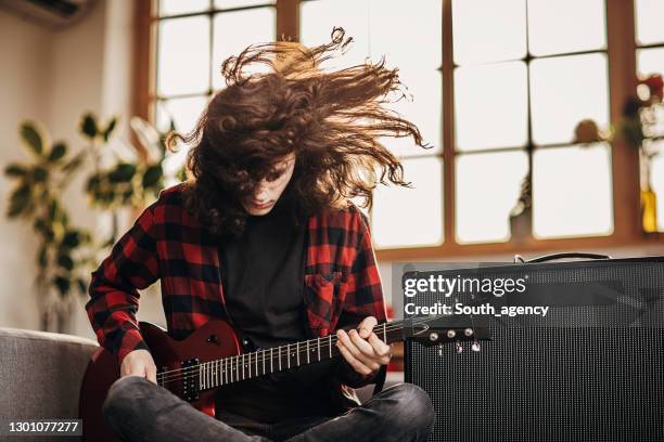 male guitarist playing electric guitar on the floor at home - headbanging stock pictures, royalty-free photos & images