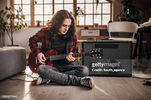 männlicher gitarrist spielt e-gitarre auf dem boden zu hause - playing electric guitar stock-fotos und bilder