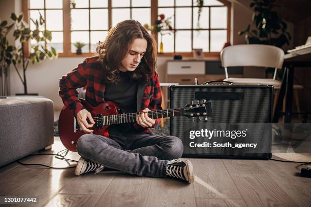 male guitarist playing electric guitar on the floor at home - guitar amp imagens e fotografias de stock