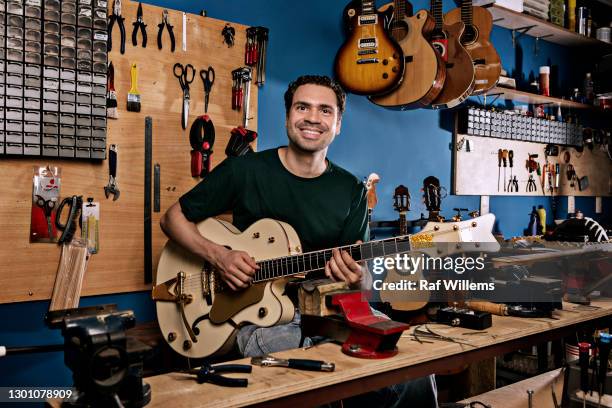 young man playing guitar in a shop. - instrumentenmaker stockfoto's en -beelden