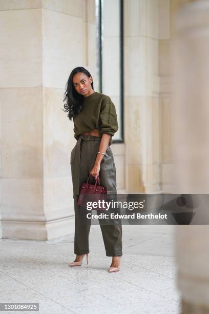 Emilie Joseph wears a green wool khaki cropped bare-belly pullover from Mango, green khaki cargo leather pants with side-pockets from Mango, a...