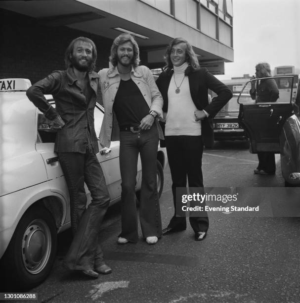 Pop group the Bee Gees arrive at Heathrow Airport in London, UK, 21st July 1973. From left to right, they are brothers Maurice, Barry and Robin Gibb.