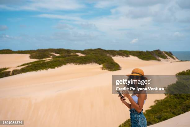 touriste utilisant le smartphone sur les dunes à genipabu - natal brésil photos et images de collection