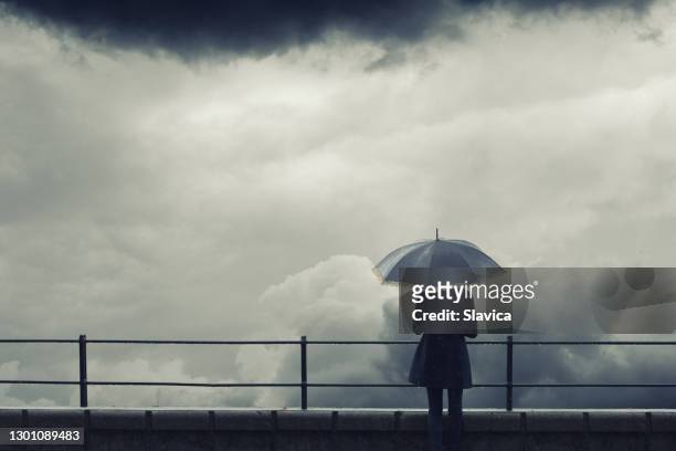 vrouw met paraplu die stormachtige wolken in de winter let - white and black women and umbrella stockfoto's en -beelden