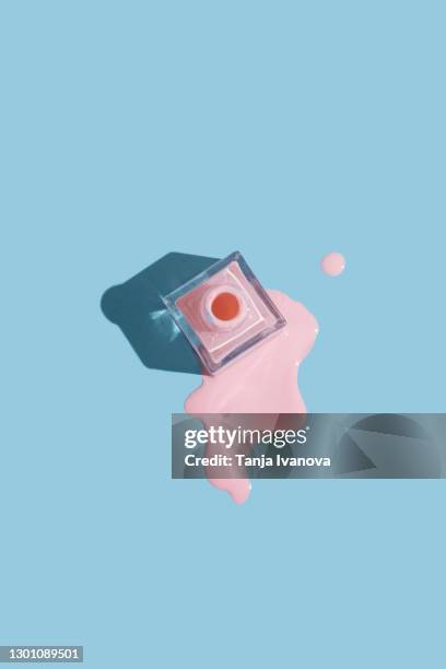 spilled bottles of pink nail polish on pastel blue background. manicure and pedicure concept. flat lay, top view, copy space - verschütten stock-fotos und bilder