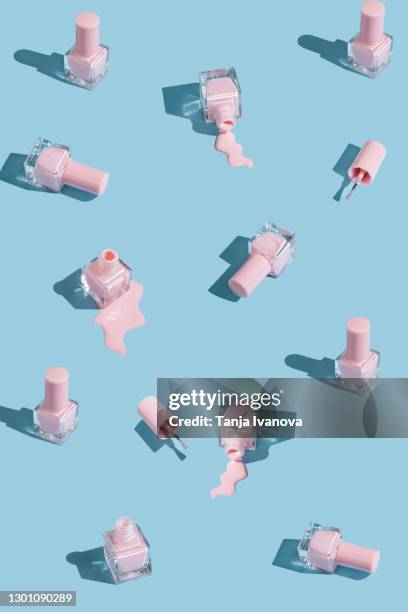 pattern made of spilled bottles of pink nail polish on pastel blue background. manicure and pedicure concept. flat lay, top view. - spijker stockfoto's en -beelden