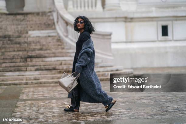 Carrole Sagba aka Linaose wears sunglasses, a black t-shirt from Uniqlo, a gray long wool cardigan from Zara, black leather pants, leather...