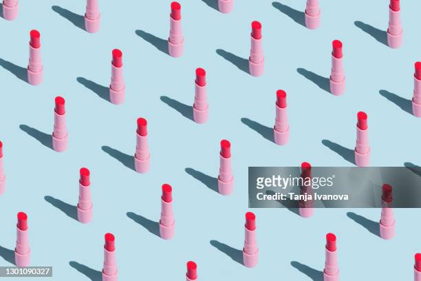 pattern made of pink lipstick with sun shadows on pastel blue background. flat lay, top view. beauty and cosmetics background. - rossetto foto e immagini stock