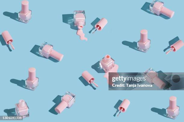 pattern made of spilled bottles of pink nail polish on pastel blue background. manicure and pedicure concept. flat lay, top view - verniz-para-unhas imagens e fotografias de stock