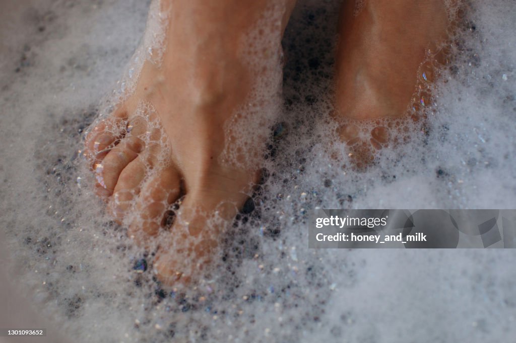 Close-up of a woman's feet covered in soap suds