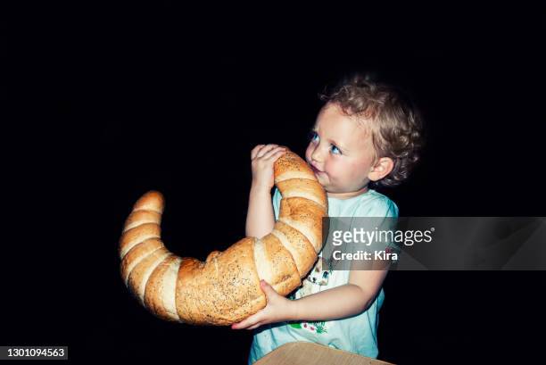 close-up of a girl eating a giant croissant - people from the back stock-fotos und bilder
